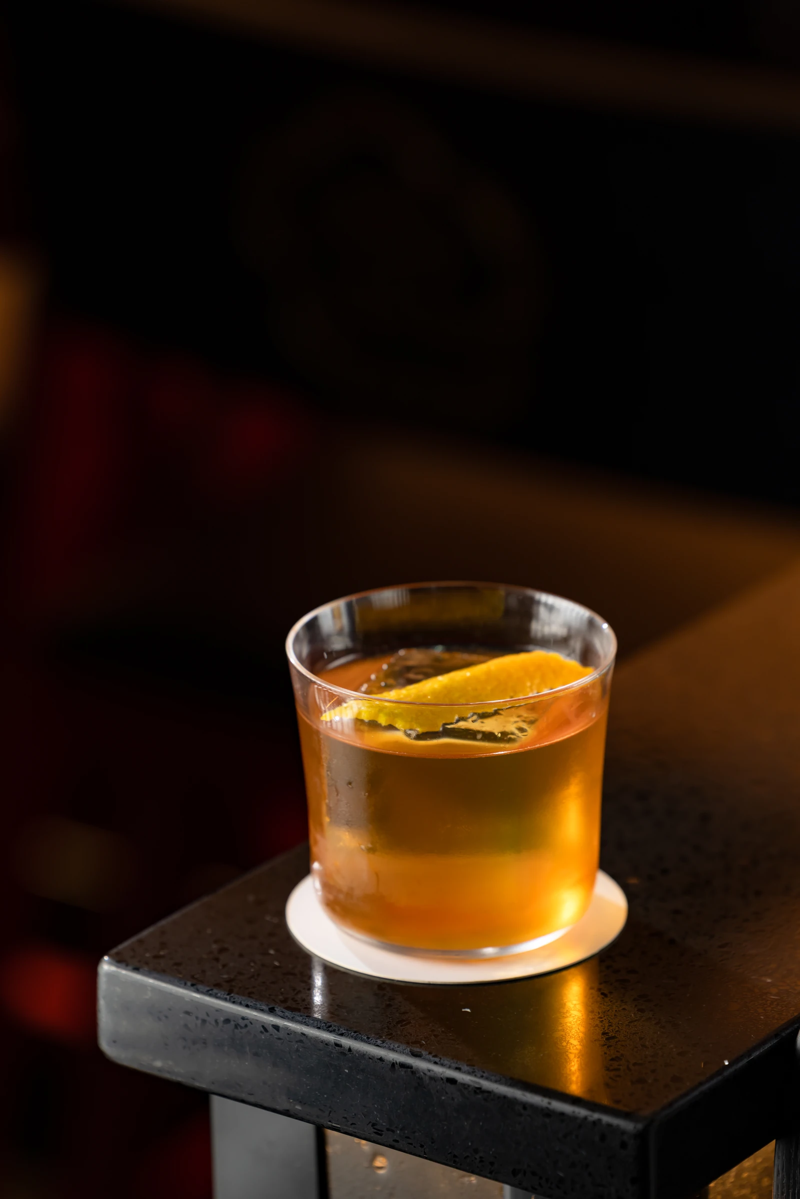 Amber cocktail over ice with a citrus peel in a rocks glass